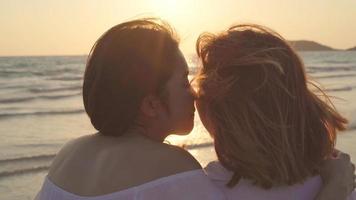 jonge Aziatische lesbisch koppel zoenen in de buurt van strand. mooie vrouwen lgbt paar gelukkig ontspannen genieten van liefde en romantisch moment bij zonsondergang in de avond. levensstijl lesbisch koppel reizen op strand concept. foto