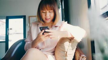 zakelijke freelance aziatische vrouw die smartphone gebruikt om te praten, lezen en sms'en zittend op tafel in café. levensstijl slimme mooie vrouwen werken bij coffeeshop concept. foto