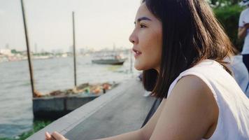 jonge aziatische vrouw blogger toerist met casual blik op de voorkant van de haven en boot op de rivier voel me ontspannen gelukkig vreugdevol reizen in café in de stad, lifestyle toeristische reizen vakantie concept. foto