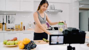 blogger sportieve aziatische vrouw die camera gebruikt om video van appelsap te maken voor haar abonnee, vrouw gebruikt biologisch fruit om thuis appelsap te maken. gezond voedselconcept. foto