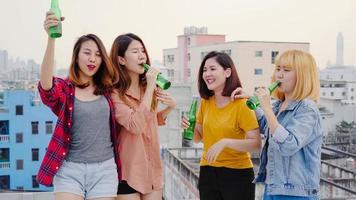 groep jonge Aziatische vrouwen mensen dansen en hun armen in de lucht opheffen op de muziek gespeeld door dj bij zonsondergang urban party op het dak. jonge Aziatische meisjesvrienden die uit met dranken hangen. foto