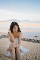jonge Aziatische vrouw zittend op hangmat ontspannen op het strand, mooie vrouwelijke gelukkig ontspannen in de buurt van zee. levensstijl vrouwen reizen op strand concept. foto