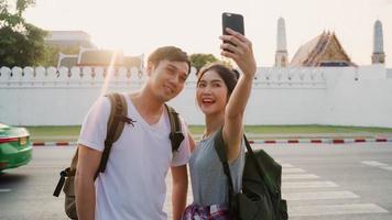 aziatisch blogger-paar reist in bangkok, thailand, lief stel met behulp van mobiele telefoon selfie en fotoweergave terwijl ze zoete tijd doorbrengen op vakantiereis bij zonsondergang. paar reizen in stadsconcept. foto