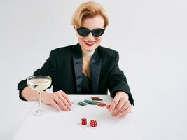 volwassen stijlvolle vrouw in zwarte smoking en zonnebril blij om te winnen in casino. gokken, mode, hobbyconcept. foto