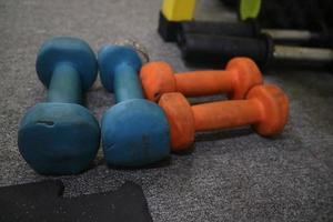 redactioneel beeld van enkele blauworanje halters op het tapijt om te oefenen in de sportschool foto