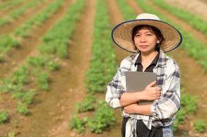 een boerin met een tablet staat op de biologische moestuin. foto