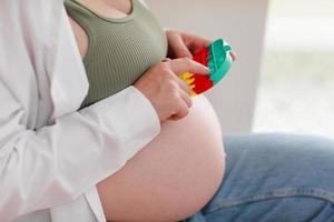 zwangere vrouw met dikke buik vergevorderde zwangerschap gebruikt anti-stress speelgoed poppit en zit thuis op een stoel. angst en nervositeit voor de bevalling. gezonde zwangerschap en gelukkig moederschap. foto