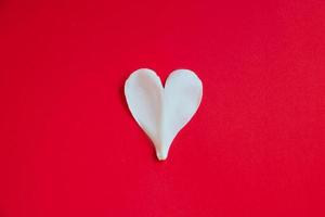 witte bloemblaadje in de vorm van hart op rode achtergrond. Valentijnsdag symbool. foto