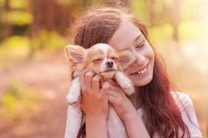 positieve emotie bij een kind met een mini-chihuahuahond in haar armen. tedere relatie met een huisdier. foto