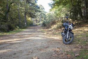 motorfiets alleen op de weg. toeren in het bos. motorfiets op de bosweg. motorfiets in de natuur parkeren op een pad. foto