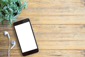 smartphone wit scherm, witte oortelefoon en op houten tafel achtergrond