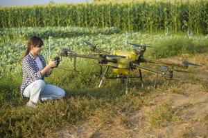 jonge slimme boer die drones bestuurt die kunstmest en pesticiden over landbouwgrond sproeien, geavanceerde technologische innovaties en slimme landbouw foto