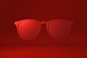 rode bril drijvend op rode achtergrond. minimaal concept idee creatief. monochroom. 3D render. foto