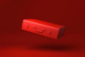 rode reiskoffer die op rode achtergrond drijft. minimaal concept idee creatief. monochroom. 3D render. foto