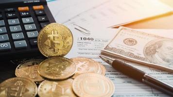 bitcoins met ons belastingformulier 1040. gouden bitcoin op belastingformulier met ons geldcalculator en pan. 2022 belastingformulier betalen concept. foto