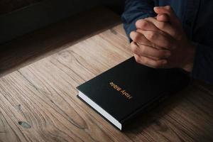man leest en bidt de Schrift of heilige bijbel op een houten tafel met kopieerruimte. religie, geloof concept. foto