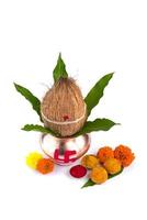 koperkalash met kokos, mangoblad, haldi, kumkum en snoepjes met goudsbloembloemdecoratie op een witte achtergrond. essentieel in de hindoeïstische puja. foto