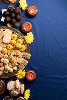 traditionele Indiase zoetigheden op blauwe achtergrond met kaarsen en bloemen plat gelegd foto