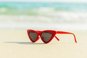 rode zonnebril op het zand mooie zomerstrand foto