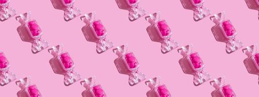 transparante snoep vormige doos met zoete hart lolly's met harde schaduw op roze achtergrond met kopie ruimte. het concept van Valentijnsdag, Moederdag. patroon foto