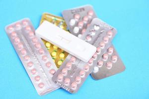 anticonceptiepillen en zwangerschapstest op blauwe achtergrond - anticonceptiemiddelen voor anticonceptie voorkomen zwangerschap foto