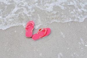 teenslippers op strand met golf zandstrand zee aan de oceaan foto