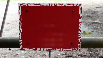 rood leeg metalen uithangbord op een hek voor het ontwerp van de artwork-sjabloon. leeg formulier. kopieer ruimte voor uw tekst of logo. foto
