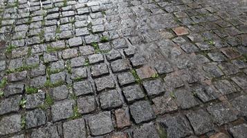 een nat trottoir zorgt voor een glanzende achtergrond. mooie grijze stenen achtergrond. stenen weg, straatstenen in de oude stad tijdens de regen overdag. foto