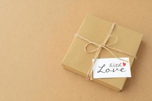 geschenkdoos in kraftpapier met liefdeskaart op een kartonnen achtergrond, kopieer ruimte. Valentijnsdag foto
