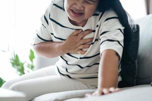 close-up van Aziatische vrouw met een hartaanval. vrouw die de borst aanraakt en pijn op de borst heeft. gezondheidszorg en medisch concept. foto
