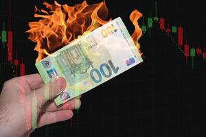 hand met een brandend eurobankbiljet met een grafiek van de financiële markt zwart foto