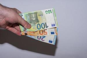 drie eurobankbiljetten in de ene hand op de bodem gehouden met grijs foto