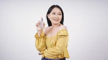 mooi Aziatisch meisje dat haar parfum toont dat op witte achtergrond wordt geïsoleerd foto