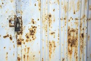 oude metalen poort bedekt met roest met een nieuw zwart slot. foto