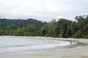 tropisch bos rond het strand in nationaal park. incidentele mensen lopen op het zand. Costa Rica foto