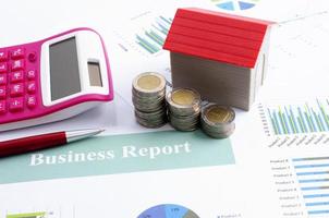 close-up van geldmuntenstapel met rood huis en pen roze rekenmachine voor bedrijfsfinanciënconcept foto