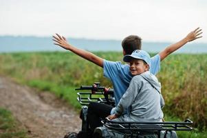 twee broers die een quad met vier wielen besturen. gelukkige kindermomenten. foto