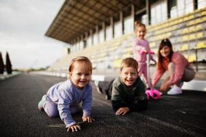 jonge stijlvolle moeder met vier kinderen buiten. sportfamilie brengt vrije tijd buitenshuis door met scooters en skates. geschilderd met krijt op het asfalt. foto