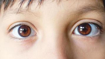 close-up mooie bruine ogen van een jonge jongen. wijd open bruine ogen kijken naar de camera foto