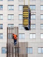 16.02.2021. kiev. Oekraïne. een bouwer met een feloranje vest en een veiligheidshelm installeert de bekisting op een stalen frame voor het daaropvolgende storten van beton. foto