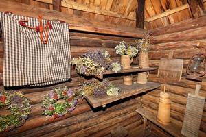 de hal van de bijkeuken van een oude landelijke hut is gevuld met verschillende huishoudelijke houten gebruiksvoorwerpen en bossen gedroogde kruiden. foto