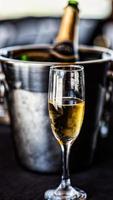 glas champagne voor champagne-emmer met fles erin foto