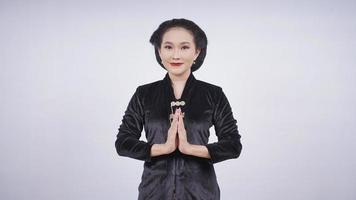 Aziatische vrouw in kebaya glimlachend gebaren welkom geïsoleerd op witte achtergrond foto