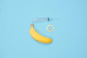 spuit, banaan en anticonceptie geïsoleerd op blauwe achtergrond foto