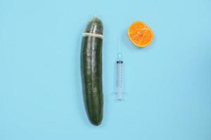 komkommer, spuit en anticonceptie geïsoleerd op blauwe achtergrond foto