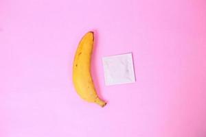 banaan en anticonceptie geïsoleerd op roze achtergrond foto