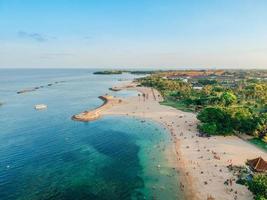 luchtfoto drone uitzicht op vakantie in sanur beach, bali, indonesië met oceaan, boten, strand, villa's en mensen. foto