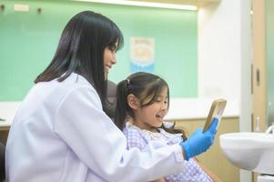 een klein schattig meisje met tanden onderzocht door tandarts in tandheelkundige kliniek, tandencontrole en gezond gebit concept foto