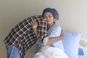 senior man op bezoek bij kankerpatiënt vrouw met hoofddoek in ziekenhuis, gezondheidszorg en medisch concept foto