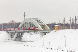 een bevroren rivier met een brug en een rijdende trein foto